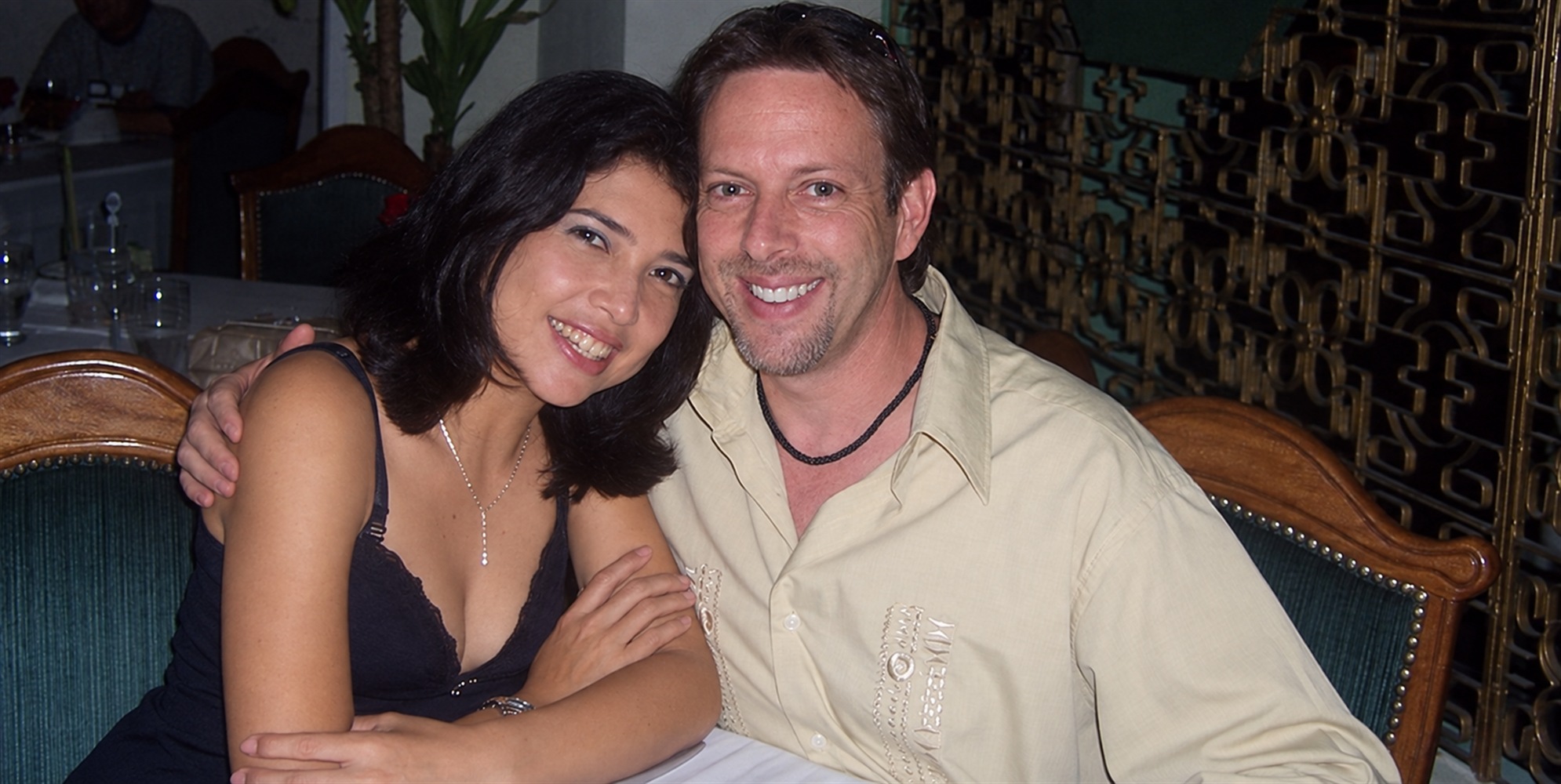 Pareja sentada junta, con el brazo de él sobre el hombro de ella.