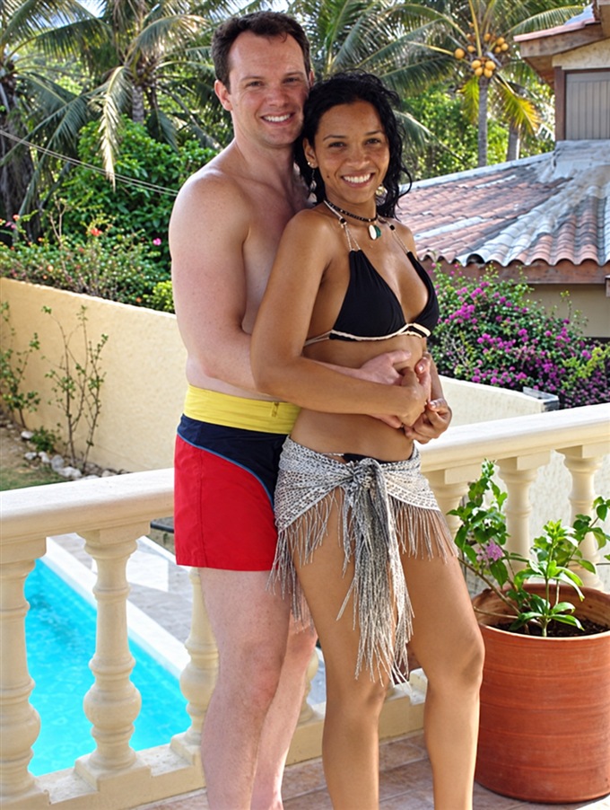 Pareja en traje de baño abrazada junto a una piscina.